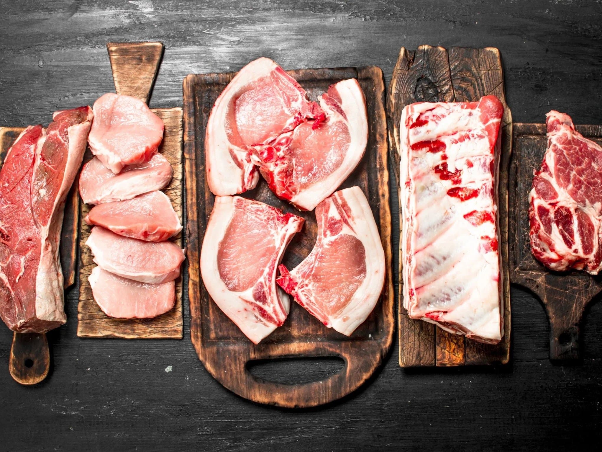 Fresh pork chops and cuts on a wooden cutting board